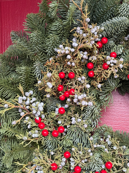 Fresh evergreen wreath with frosty blue juniper berries and red berry clusters
